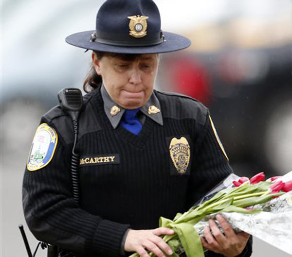 Newtown Police Officer Maryhelen McCarthy places flowers at a makeshift memorial outside St. Rose of Lima Roman Catholic Church on Sunday in Newtown, Conn.