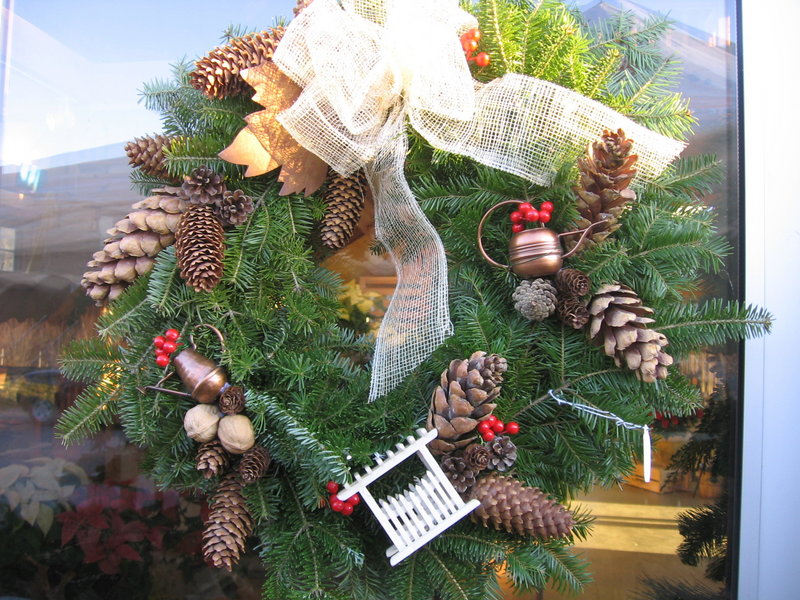 A gardeners’ wreath is decorated with mini watering cans, a tiny picket fence, pinecones, berries and a burlap bow. A themed wreath can be a really fresh addition to your holiday decor.