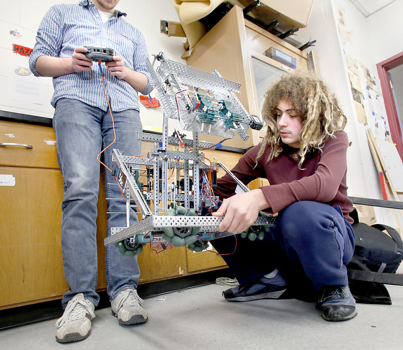 Matthew Reale-Hatem, 16, a junior, holds up a robot as Ian Schrank, also 16 and a junior, operates the controls as they troubleshoot a problem Friday.