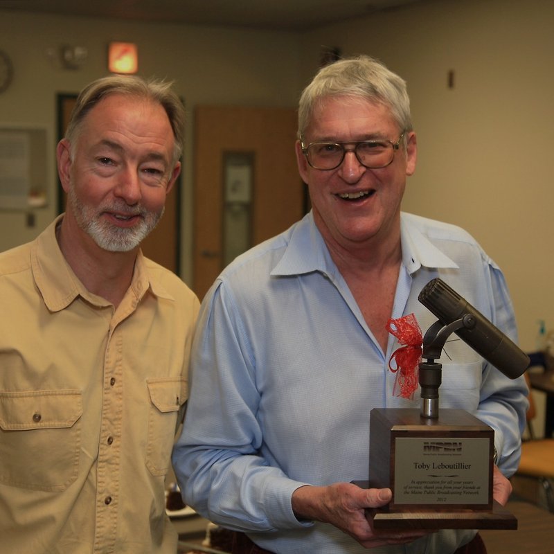 MPBN program director Charles Beck, left, enjoys a moment with Toby Leboutillier, holding a microphone, after Friday’s airing of “Down Memory Lane.”