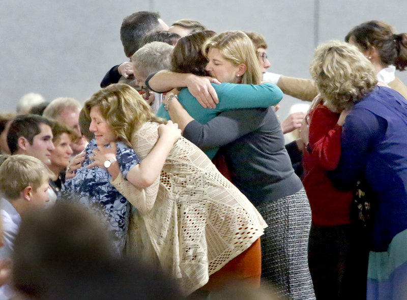 Falmouth Elementary School second-grade teachers hug members of Kevin Grover’s family after speaking during the Celebration of Life for Kevin Grover at Falmouth High School on Saturday.