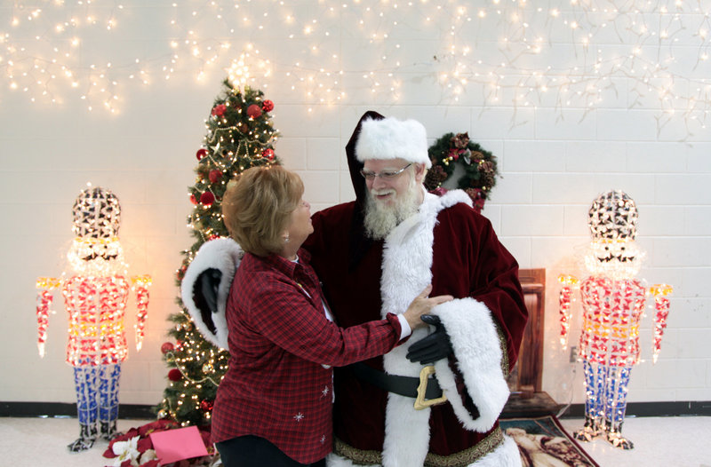 John Parks, in the role of Santa Claus, receives a welcome from school principal Carol Winters while greeting students last week at Newton Lee Elementary School in Ashburn, Va.