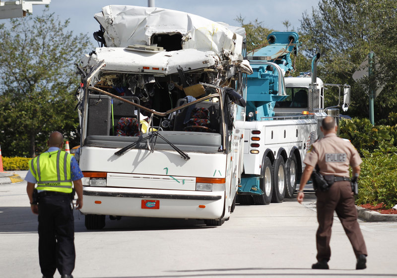 Police watch as a bus that hit a concrete overpass at Miami International Airport is hauled away Saturday. The vehicle was too tall for the 8-foot-6-inch overpass.