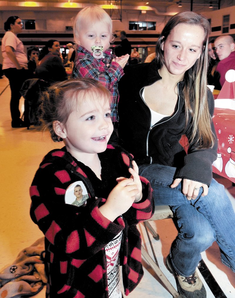 Cheyenne Allen, 3, of Strong, wearing a button with a photo of her father, Sgt. Sheldon Allen, reacts as Santa enters the Armory in Waterville on Sunday. With her are mother Emma and brother Elias.