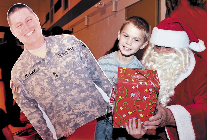 Colby Peacock of Yarmouth gets a present from Santa while holding a large photo he brought of his father, 1st Sgt. Michael Peacock, during a Christmas party for families of soldiers in Unit 488 serving in Afghanistan, in Waterville on Sunday.