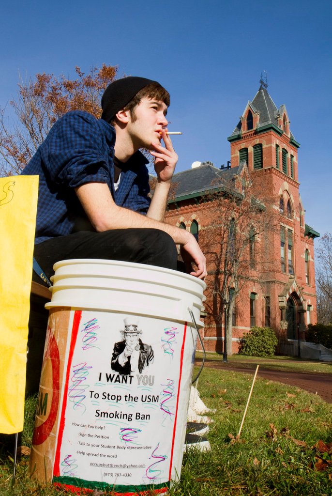 USM freshman Joshua Thornberg smokes during a protest of a proposed smoking ban on USM campuses at the Gorham campus on Monday. Buckets like this one were made by protest organizers and placed around campus.