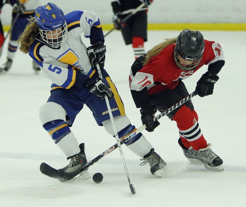 Meg Pierce, left, of Falmouth battles for control of the puck with Scarborough’s Rachel Wallace Monday night at Falmouth. Unbeaten Scarborough won 7-0 against the defending Western champions.