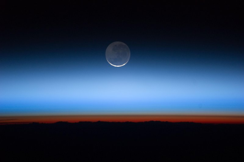 Image from the Expedition 28 crew on the International Space Station shows the moon with the Earth near the bottom transitioning into the troposphere, the lowest and most dense portion of the Earth’s atmosphere.