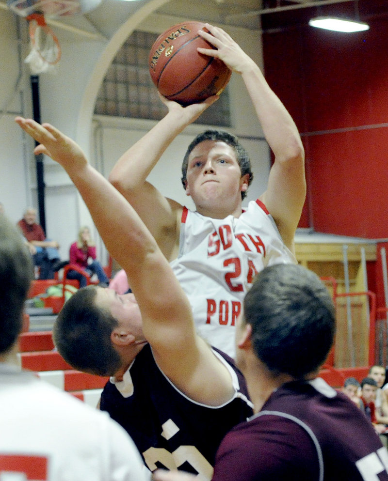 Conner MacVane of South Portland keeps his eyes on the basket while lofting a shot over Shaun Francoeur of Windham at Beal Gym.