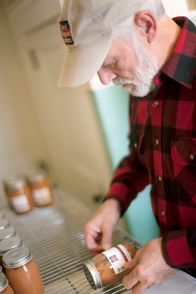 Cheryl Wixson’s husband Phil labels jars of applesauce. Last year, he labeled 10,000 jars of Cheryl Wixson’s Kitchen foods; this year, the output is 30,000 jars.