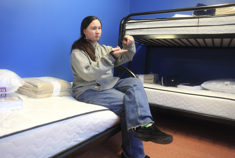 Crystal Swain, a homeless teen who has spent time at the Preble Street teen shelter, describes the width of the older shelter mattress compared to the new one she is sitting on.