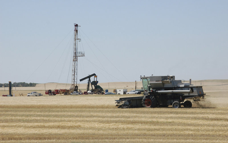 A combine cutting durum wheat near an oil well in Tioga, N.D. demonstrates the intersection of energy production and the environment. Critics of booming gas and oil production are concerned about the effects that pollution has on climate change generally, but also on the possible health consequences from breathing smog, soot and other pollutants.