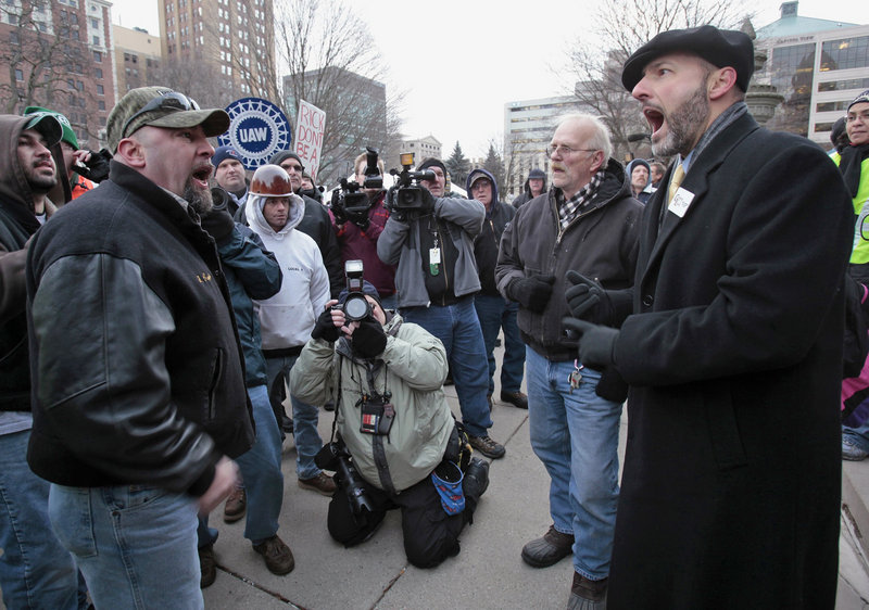 A union activist, left, goes jaw to jaw with a “right to work” proponent during an emotional rally in Lansing, Mich., Tuesday after the Republican-led legislature gave final approval to “right to work” legislation.