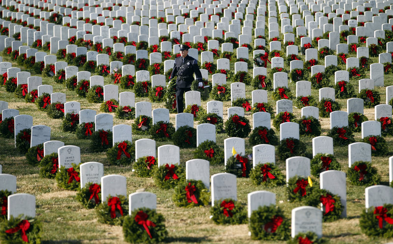 Portland police officer Terry Fitzgerald helps lay holiday wreaths at graves at Arlington National Cemetery on Saturday, or Wreaths Across America Day, an event that has expanded to all 50 states since it was started in 1992 by Maine businessman Morrill Worcester.