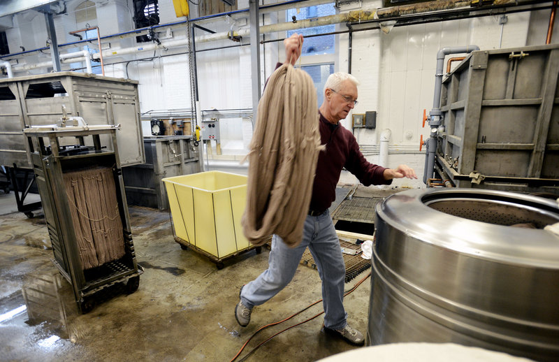 Don Morton, the dye master, carries yarn to a water extractor at the Saco River Dyehouse in Biddeford. Morton was the dye master at JCA in Massachusetts before it closed.