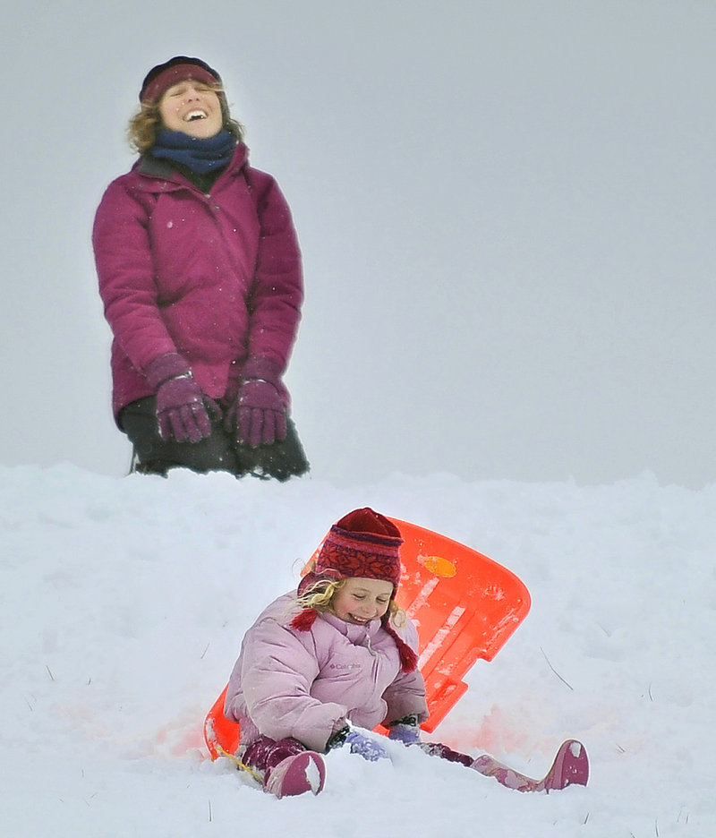Jessica Plumb, top, of Port Townsend, Wash., laughs as her daughter, Zia Bell Plumb Magill, 6, stumbles in the snow while sledding on Portland's Eastern Promenade on Monday, Dec. 17, 2012. They said their only wish while visiting family for the holidays was that it would snow.