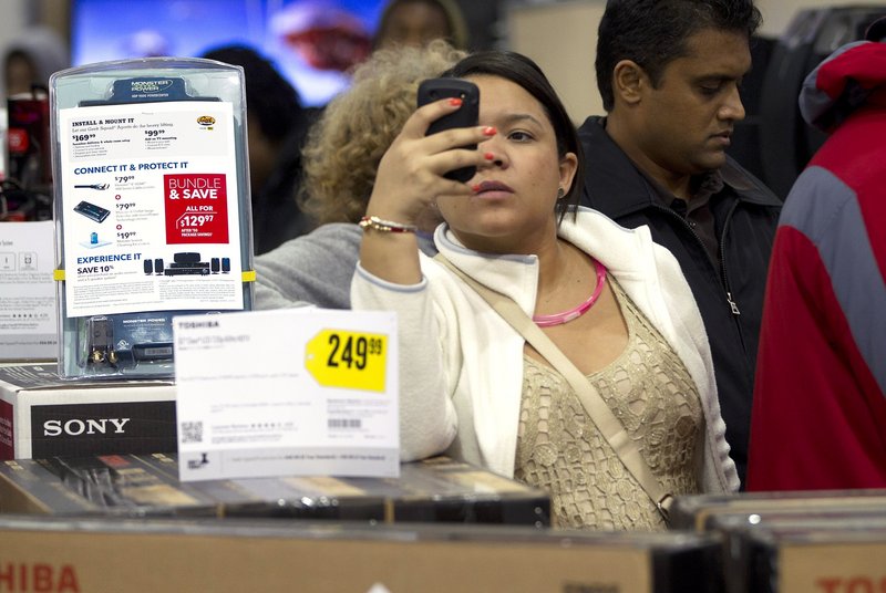 A shopper uses her smart phone at the Pembroke Pines, Fla. Best Buy. Whether shoppers know it or not, their actions on Facebook and other online sites help dictate what’s in stores during this holiday season.