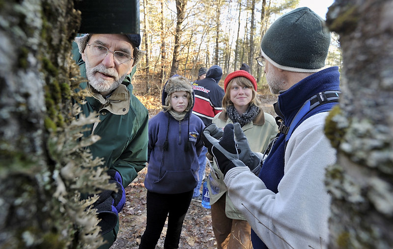 Joe Barth, left, inspects the lung lichen on a tree during a hike of two trails in the Hidden Valley Nature Center while retired teacher and volunteer Chuck Dinsmore, right, lectures to Hannah Lee Mencher and Sarah Wineberg.