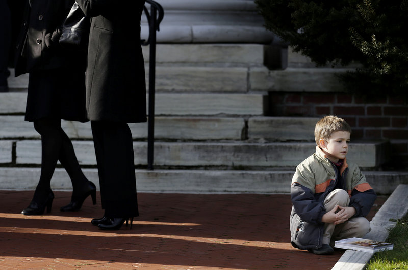 A boy sits near the steps of a church a church before the memorial service for Lauren Rousseau in Danbury, Conn., Thursday, Dec. 20, 2012. Rousseau, 30, was killed when Adam Lanza walked into Sandy Hook Elementary School in Newtown, Dec. 14, and opened fire, killing 26 people, including 20 children, before killing himself. Arming teachers in response to the school shootings last week in Newtown, Conn., would not be a good way to make schools safer, public safety officials in Maine said Friday. (AP Photo/Seth Wenig)