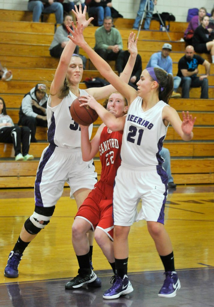 Heather LeBlanc of Sanford can’t find room to get off a shot while guarded by Deering’s Marissa MacMillan, left, and Alexis Stephenson.