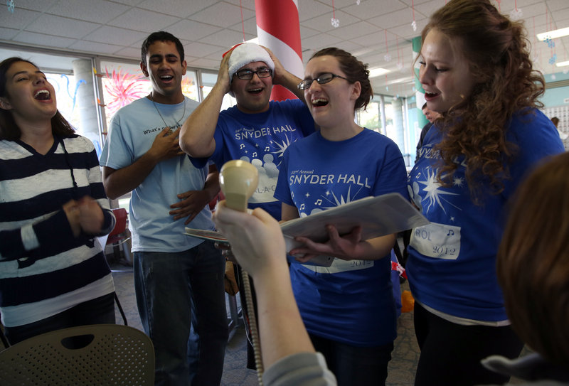 University of Illinois students, from left, Katy Pippins, Warren D’Souza, Jose Cuevas, Clare Curtin and Kasia Stelmach sing “Feliz Navidad” for a “Dial-a-Carol” caller. Volunteers manning the 24/7 service during finals week fielded 500 calls on the first day this year.