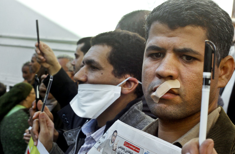 Egyptian journalists tape their mouths and raise their pens during a demonstration against the Islamist-backed constitution in Cairo on Sunday. Egypt’s opposition fears that freedom of the press will be limited under the increasingly religious government.