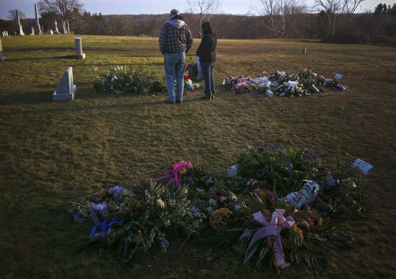 Visitors stand over the grave of 6-year-old Jack Pinto, one of 20 schoolchildren killed in the Dec. 14 shootings at Sandy Hook Elementary School, in Newtown Village Cemetery in Connecticut on Monday. The graves of Pinto’s classmates, 6-year-old Allison Wyatt and 6-year-old Ana Grace Marquez-Green, are seen in the foreground and at right.