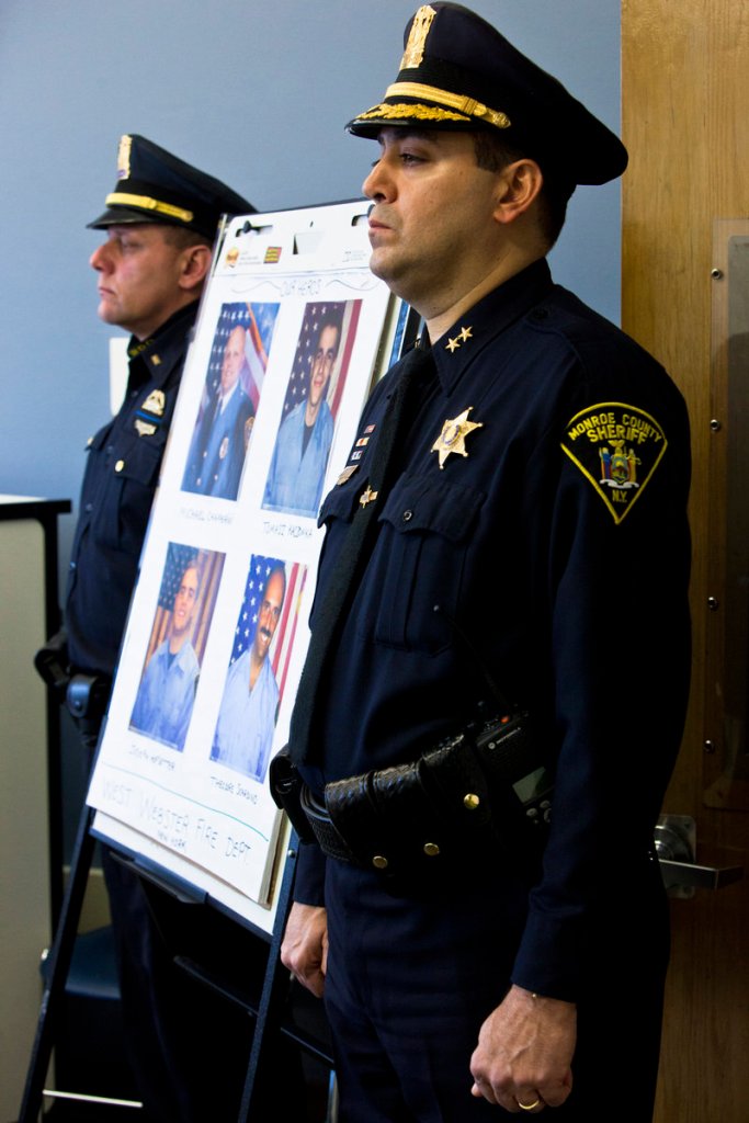 Monroe County Sheriff Deputy Chief Steve Scott, right, and Webster Police Lt. Joseph Rieger stand by a photo of the dead and wounded firefighters during a news conference in Webster, N.Y., on Christmas Day.