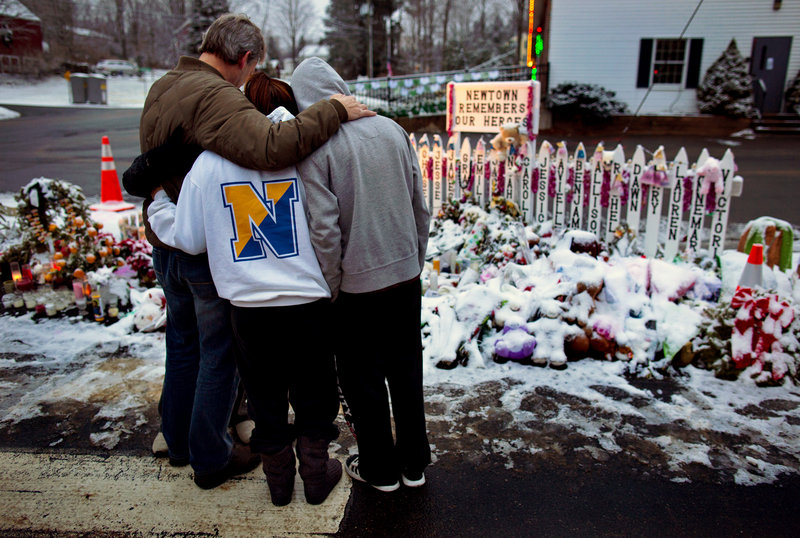 A family visits a memorial Tuesday at the firehouse in Newtown, Conn., where a gunman killed 20 students and six educators at Sandy Hook Elementary School on Dec. 14. Police have yet to offer a theory about a possible motive for the gunman.