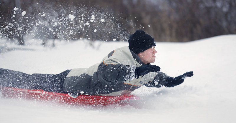 Jason Eisenhuth of Portland demonstrates his "no hands" sledding ability at Portland's East End on Thursday. A winter storm dumped about a foot of snow on southern Maine, closing state offices, making roads slick and canceling many flights at the Portland International Jetport.