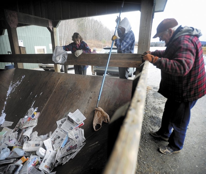 Reggie Lane, center, an employee at the Wilton Transfer Station, fishes a plastic bag out of the dumpster as Lawrence Farrington, right, and his wife, Marcella, look on.