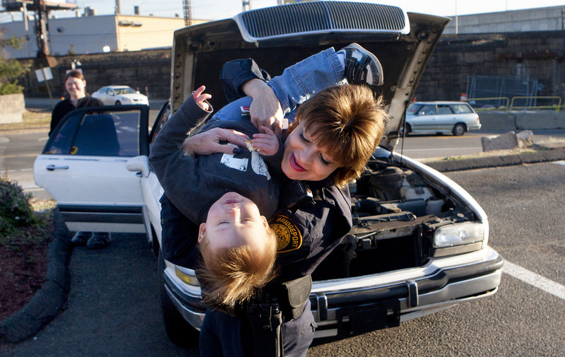 Amanda Arnold watches as Bridgeport Police Sgt. Melody Pribesh plays with her 19-month-old son, Kason, after getting her car fixed in Bridgeport, Conn. Officers fixed Arnold’s car after it broke down late at night while she was traveling to Florida.
