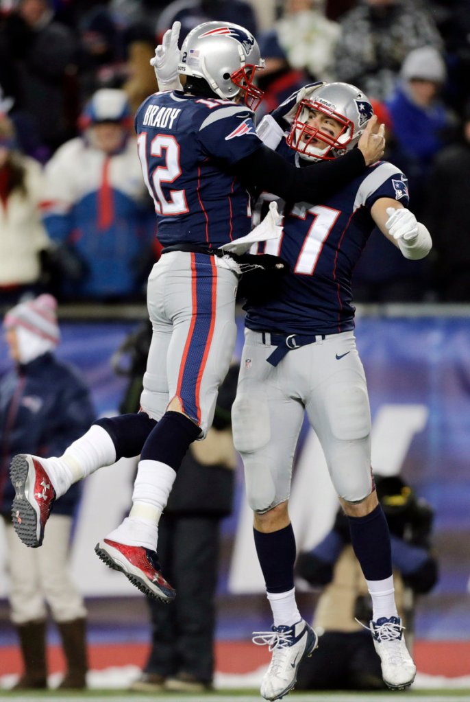 New England’s Tom Brady, left, celebrates a touchdown pass with tight end Rob Gronkowski during the Pats’ 28-0 whitewash of Miami on Sunday in Foxborough, Mass.