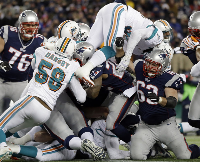 New England’s Stevan Ridley, center, is surrounded by Dolphins, including linebacker Karlos Dansby (58), as he scores a touchdown in the second quarter of the Patriots’ 28-0 win at home on Sunday.
