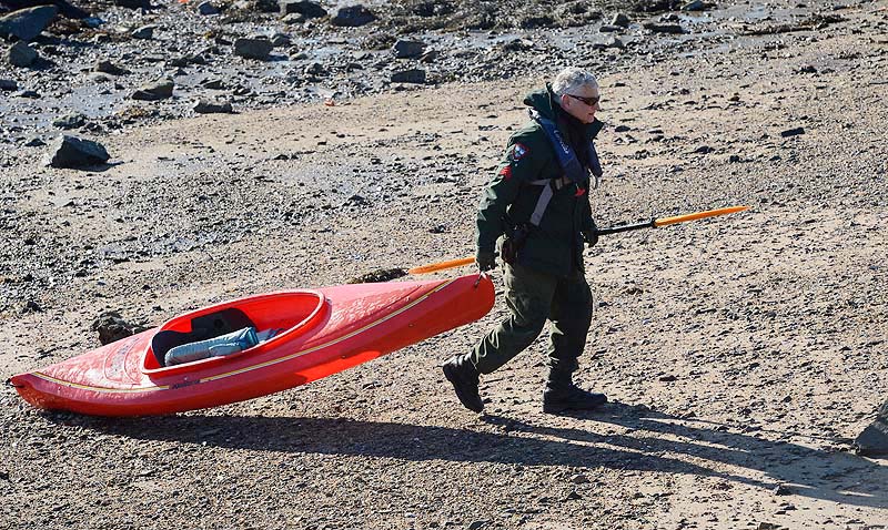 Maine Warden Service Sgt. Tim Spahr drags a kayak onto shore Monday at Cape Porpoise where the search for Zachary Wells and Prescott Wright continues.