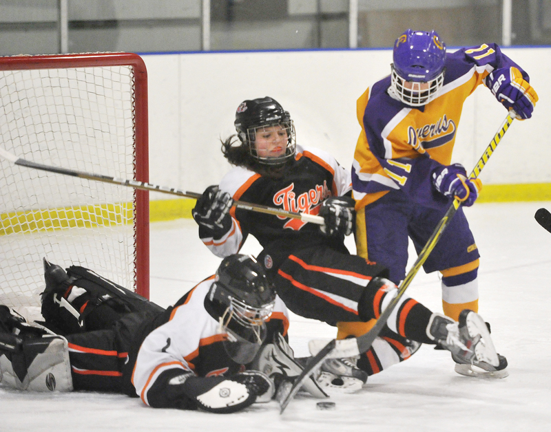 Cassie Ellis, Biddeford’s goalie, covers a shot by Cheverus’ Sophia Giancotti as Katherine Dumoulin helps out for the Tigers before falling to the ice in Wednesday’s girls’ hockey game in Portland. Cheverus won in OT, 6-5.