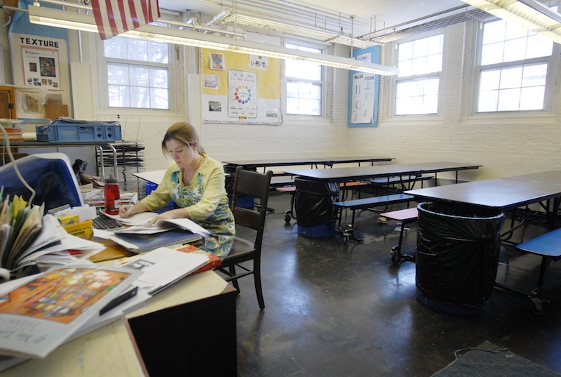In this 2007 file photo, Maryjane Johnston, an art teacher at the former Nathan Clifford Elementary School in Portland, works at her desk during recess. A proposal to shift half of Maine's contribution to teacher retirement costs from the state to local school districts would disproportionately affect wealthier communities.