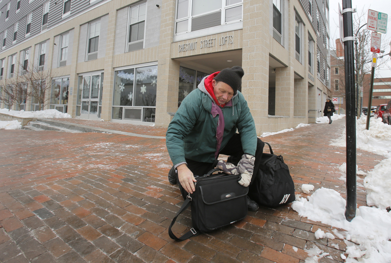 Charles Jones, 55, zips up his bags at the corner of Chestnut Street and Cumberland Avenue Friday morning on his way to the Portland Public Library.