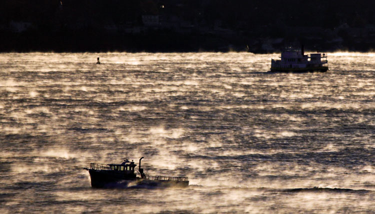 Arctic sea smoke, created when very cold air touches warmer water, surrounds boats as they head out into Casco Bay just before sunrise Wednesday morning.