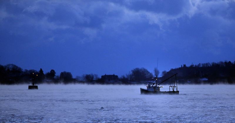 A groundfishing vessel glides out into Casco Bay before dawn on Jan. 23 as arctic sea smoke rises from the water.