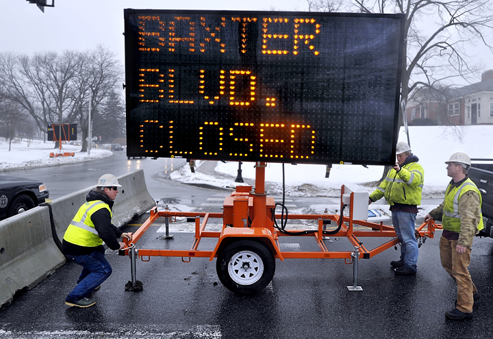 Cody Jean, foreman for the Sargent Corp., left, and his crew, Billy Ruff, program the sign message, and Seth Watts, right, sets up a flashing sign to warn motorists of the closing of Baxter Boulevard from Vannah Avenue to Bates Street until June for storm drain and holding tank replacement.