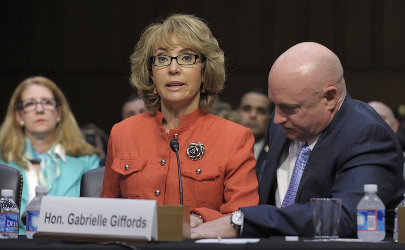 Former Arizona Rep. Gabrielle Giffords, who was seriously injured in the mass shooting that killed six people in Tucson, Ariz. two years ago, sits with her husband Mark Kelly, speaks on Capitol Hill in Washington, Wednesday, Jan. 30, 2013, before the Senate Judiciary Committee hearing on gun violence. (AP Photo/Susan Walsh)
