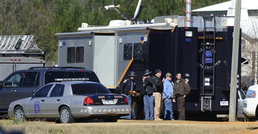 Law officers stand beside the Alabama State trooper mobile command post at the Dale County hostage scene in Midland City, Ala. on Thursday, Jan. 31, 2013. A gunman holed up in a bunker with a 6-year-old hostage has kept law officers at bay since the standoff began when he killed a school bus driver and dragged the boy away, authorities said. (AP Photo/Montgomery Advertiser, Mickey Welsh)