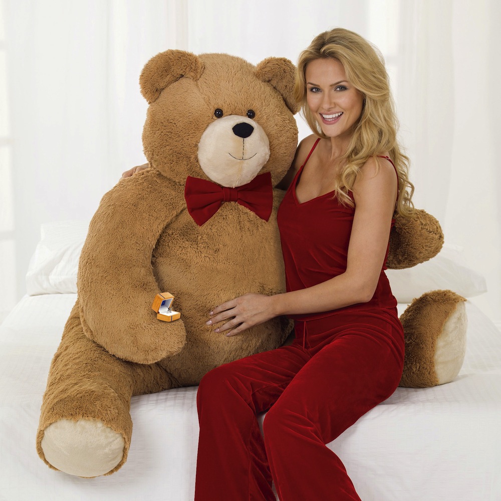 In this photo released by Vermont Teddy Bear, a model poses with the the Big Hunka Love Diamond Bear. The Shelburne, Vt.-based company has put a $30,000 price tag on the 4½-foot-tall bear. That’s because the bulk of the price is the 5.9 carat, one-of-a-kind “fire rose” diamond ring made by Perrywinkle's Fine Jewelry in Burlington. (AP Photo/Vermont Teddy Bear)