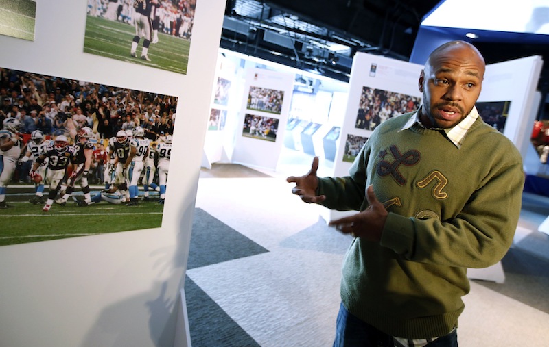 Former New England Patriots running back Kevin Faulk speaks to a reporter while touring an exhibit of NFL football photographs by sports photographer Dick Raphael at The Hall at Patriot Place in Foxborough, Mass., Wednesday, Dec. 19, 2012. The photograph at left shows Faulk (33) during a game against the Carolina Panthers. (AP Photo/Michael Dwyer)