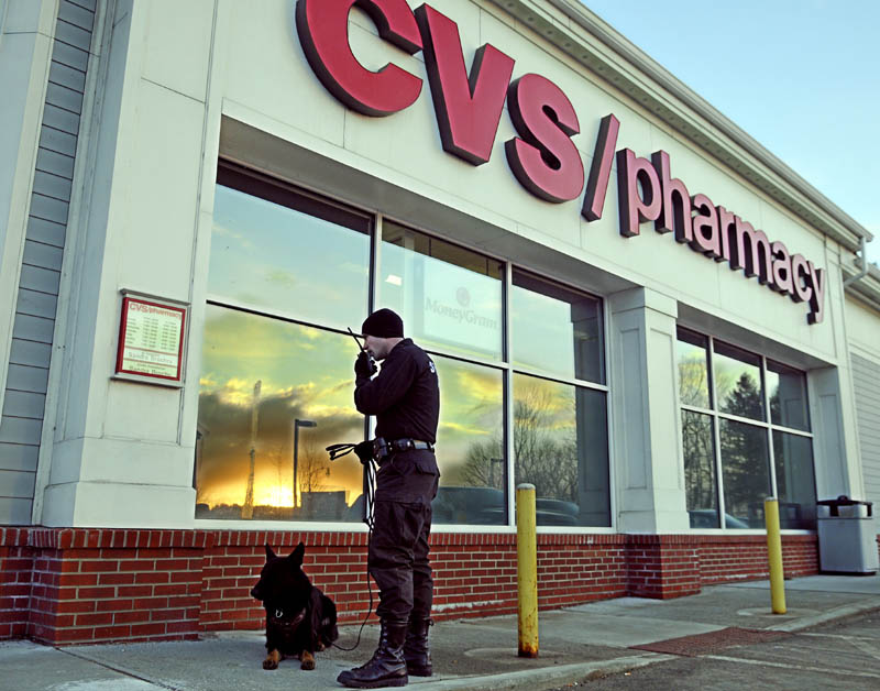 ROBBED: Cpl. G.J. Neagle of the Kennebec County Sheriff's Office speaks on the radio late Tuesday afternoon outside the CVS pharmacy on Stone Street in Augusta moments after it was reportedly robbed. Police were pursuing the robbers on foot, by vehicle and with dogs, such as Neagle's.