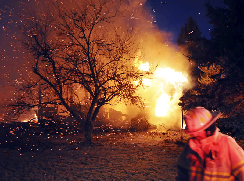 A firefighter walks by the blaze on the Crummett Mountain Road in Somerville Thursday night. Investigators found a body in the rubble and believe it is the homeowner, 92-year-old Cecil Brann.