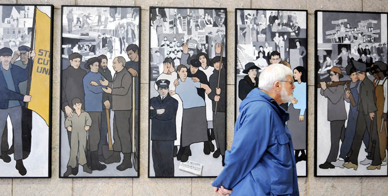 Ken Jones of Farmingdale on Monday examines the labor murals that are now hanging on the wall of the Cultural Building atrium that serves as the entryway to the Maine State Museum in Augusta.