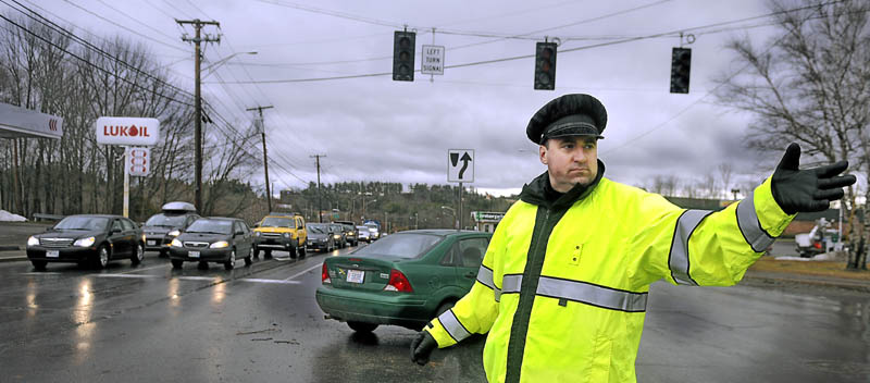 Augusta Police officer Paul Doody directs traffic at an intersection on Western Avenue Thursday following widespread power outages from high winds. Thousands of Maine residents were without power from gusts that reached up to 50 miles per hour.