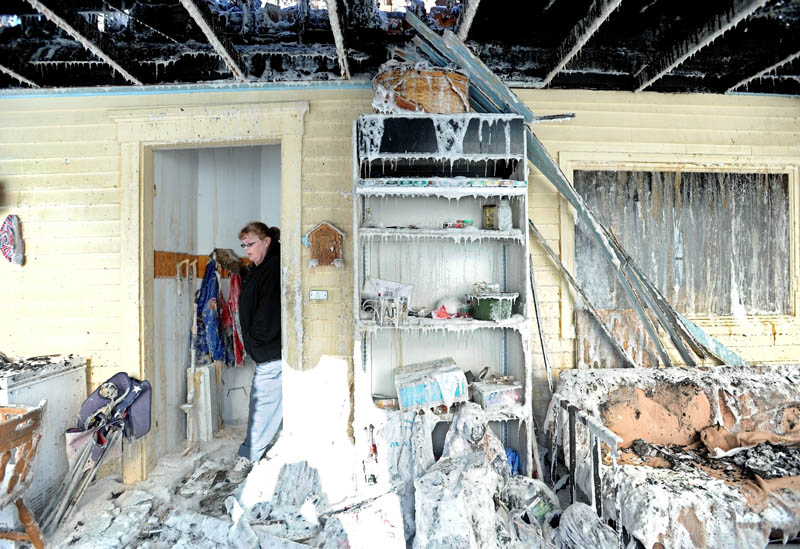 Becky Williams, 40, walks through the iced-over entryway of her parents' Madison Avenue home, in Madison, which was destroyed by fire around 3 a.m. Friday. Six area fire departments responded to the blaze in temperatures below 0 degrees.